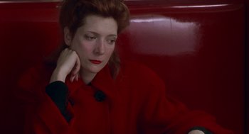 Movie still from “Dick Tracy” (1990), directed by Warren Beatty – A woman sitting on a red bench with her head resting on her hand; Close Up shot, High angle