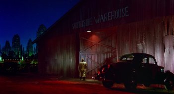 Movie still from “Dick Tracy” (1990), directed by Warren Beatty – A man walking in front of a warehouse at night; Extreme Wide shot, Low angle
