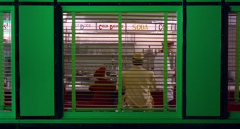 Movie still from “Dick Tracy” (1990), directed by Warren Beatty – Two people are sitting in a restaurant behind bars; Wide shot, High angle