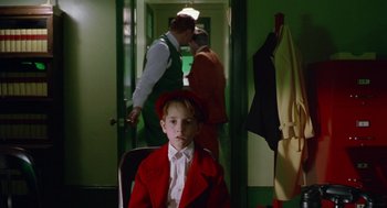 Movie still from “Dick Tracy” (1990), directed by Warren Beatty – A young boy in a red jacket and a red hat; Medium shot, Over the shoulder angle