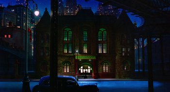 Movie still from “Dick Tracy” (1990), directed by Warren Beatty – A car parked on the side of the road in front of a building; Extreme Wide shot, High angle