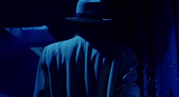 Movie still from “Dick Tracy” (1990), directed by Warren Beatty – A man wearing a blue suit and a black hat; Medium shot, Low angle