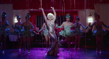 Movie still from “Dick Tracy” (1990), directed by Warren Beatty – A group of people in costumes performing a dance; Wide shot, Low angle