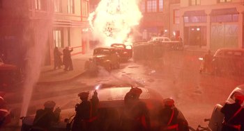 Movie still from “Dick Tracy” (1990), directed by Warren Beatty – A car on a city street being hit by an exploding object; Wide shot, High angle