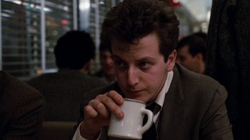 Movie still from “Diner” (1982), directed by Barry Levinson – A man in a suit and tie drinking a cup of coffee; Close Up shot, Low angle