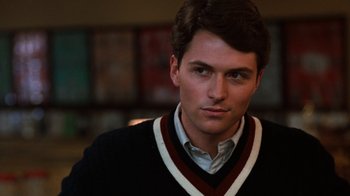 Movie still from “Diner” (1982), directed by Barry Levinson – A young man in a black and white sweater looks to his left; Close Up shot, Over the shoulder angle