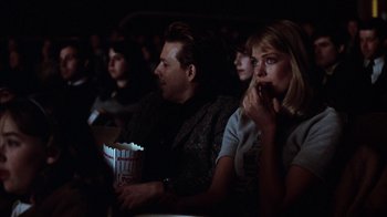 Movie still from “Diner” (1982), directed by Barry Levinson – A group of people sitting in a dark room eating popcorn; Medium shot, Over the shoulder angle