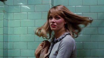 Movie still from “Diner” (1982), directed by Barry Levinson – A woman with long blonde hair standing in front of a wall; Close Up shot, Over the shoulder angle