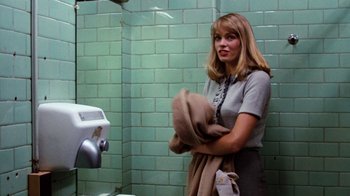 Movie still from “Diner” (1982), directed by Barry Levinson – A woman standing in front of a urinal in a public restroom; Medium shot, Over the shoulder angle