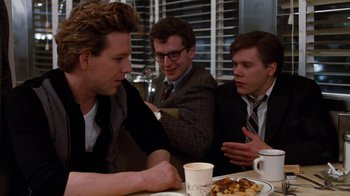 Movie still from “Diner” (1982), directed by Barry Levinson – A group of men sitting at a table with a plate of food in front of them; Medium shot, Over the shoulder angle