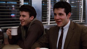 Movie still from “Diner” (1982), directed by Barry Levinson – A couple of men sitting next to each other at a table; Medium shot, Over the shoulder angle