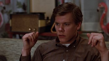 Movie still from “Diner” (1982), directed by Barry Levinson – A man sitting in front of a table with his hand up to his face; Close Up shot, Over the shoulder angle