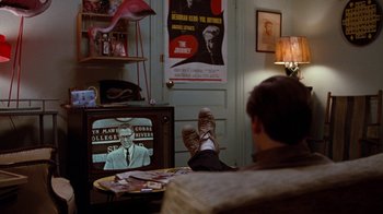 Movie still from “Diner” (1982), directed by Barry Levinson – A man sitting in front of a tv in a room; Wide shot, Over the shoulder angle
