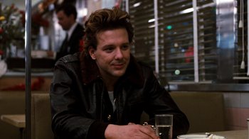 Movie still from “Diner” (1982), directed by Barry Levinson – A man sitting at a table with a glass of water in front of him; Close Up shot, Over the shoulder angle