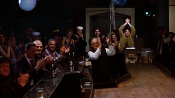 Movie still from “Diner” (1982), directed by Barry Levinson – A group of people sitting at a bar raising their hands; Wide shot, Over the shoulder angle