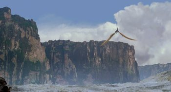 Movie still from “Dinosaur” (2000), directed by Eric Leighton – An image of a bird flying in the air over the ocean; Extreme Wide shot, Low angle