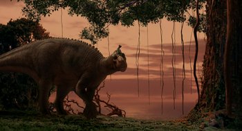 Movie still from “Dinosaur” (2000), directed by Eric Leighton – An image of an animal that is walking in the grass near a tree; Wide shot, Low angle