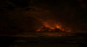 Movie still from “Dinosaur” (2000), directed by Eric Leighton – A fire is burning in the dark sky; Extreme Wide shot, Low angle