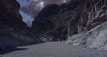 Movie still from “Dinosaur” (2000), directed by Eric Leighton – A rocky mountain with a sky filled with dark clouds; Extreme Wide shot, High angle