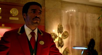 Movie still from “Dirty Pretty Things” (2002), directed by Stephen Frears – A man in a red jacket and a white tie standing next to a wall; Medium shot, Low angle