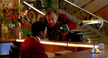 Movie still from “Dirty Pretty Things” (2002), directed by Stephen Frears – A man in a red jacket is talking to a man in a red suit; Medium shot, Over the shoulder angle