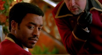 Movie still from “Dirty Pretty Things” (2002), directed by Stephen Frears – A man in a red jacket is getting his hair cut; Close Up shot, Over the shoulder angle