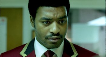 Movie still from “Dirty Pretty Things” (2002), directed by Stephen Frears – A person wearing a suit and tie; Close Up shot, Over the shoulder angle