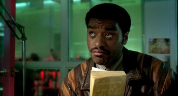 Movie still from “Dirty Pretty Things” (2002), directed by Stephen Frears – A man in a brown jacket holding a book; Close Up shot, Low angle