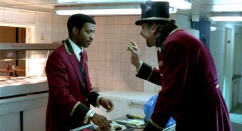 Movie still from “Dirty Pretty Things” (2002), directed by Stephen Frears – Two men in red jackets and a black hat; Medium shot, Over the shoulder angle