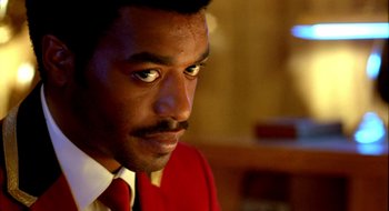 Movie still from “Dirty Pretty Things” (2002), directed by Stephen Frears – A person wearing a suit and tie; Close Up shot, Over the shoulder angle