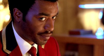 Movie still from “Dirty Pretty Things” (2002), directed by Stephen Frears – A person wearing a suit and tie; Close Up shot, Over the shoulder angle