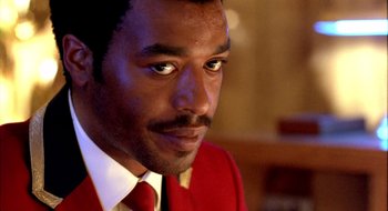 Movie still from “Dirty Pretty Things” (2002), directed by Stephen Frears – A person wearing a suit and tie; Close Up shot, Over the shoulder angle