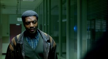 Movie still from “Dirty Pretty Things” (2002), directed by Stephen Frears – A man standing in front of a glass wall; Medium shot, Over the shoulder angle