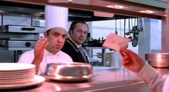 Two men in a kitchen with a metal pan