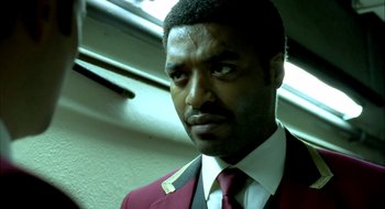 Movie still from “Dirty Pretty Things” (2002), directed by Stephen Frears – A person wearing a suit and tie; Close Up shot, Low angle