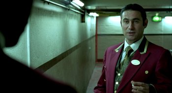 Movie still from “Dirty Pretty Things” (2002), directed by Stephen Frears – A man in a suit and tie standing in a hallway; Medium shot, Low angle