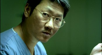 Movie still from “Dirty Pretty Things” (2002), directed by Stephen Frears – A person wearing glasses and a blue shirt; Close Up shot, Low angle