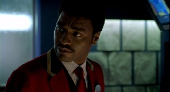 Movie still from “Dirty Pretty Things” (2002), directed by Stephen Frears – A man in a red jacket and a tie; Close Up shot, Over the shoulder angle