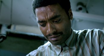 Movie still from “Dirty Pretty Things” (2002), directed by Stephen Frears – A person wearing a striped shirt; Close Up shot, Overhead angle