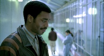 Movie still from “Dirty Pretty Things” (2002), directed by Stephen Frears – A man standing in front of two other people; Close Up shot, Over the shoulder angle