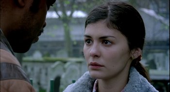 Movie still from “Dirty Pretty Things” (2002), directed by Stephen Frears – A young woman looking at the camera while a man looks at her face; Close Up shot, Over the shoulder angle