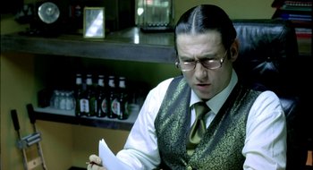 Movie still from “Dirty Pretty Things” (2002), directed by Stephen Frears – A man wearing glasses and a tie holding a paper; Close Up shot, Over the shoulder angle
