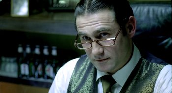 Movie still from “Dirty Pretty Things” (2002), directed by Stephen Frears – A person wearing glasses and a tie; Close Up shot, Over the shoulder angle
