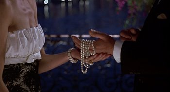 Movie still from “Dirty Rotten Scoundrels” (1988), directed by Frank Oz – A man and a woman holding hands with pearls in their hands; Close Up shot, Overhead angle