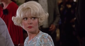 Movie still from “Dirty Rotten Scoundrels” (1988), directed by Frank Oz – An older woman with blonde hair wearing a blue dress; Close Up shot, Over the shoulder angle