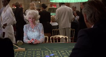 Movie still from “Dirty Rotten Scoundrels” (1988), directed by Frank Oz – A woman sitting at a table in front of a game board; Medium shot, Over the shoulder angle