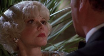 Movie still from “Dirty Rotten Scoundrels” (1988), directed by Frank Oz – An older woman with blonde hair and red lipstick; Close Up shot, Over the shoulder angle