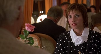 Movie still from “Dirty Rotten Scoundrels” (1988), directed by Frank Oz – A woman sitting at a table with a pink rose in front of her; Close Up shot, Over the shoulder angle