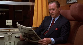 Movie still from “Dirty Rotten Scoundrels” (1988), directed by Frank Oz – A man sitting at a table reading a newspaper; Close Up shot, Low angle