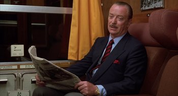 Movie still from “Dirty Rotten Scoundrels” (1988), directed by Frank Oz – A man sitting in a chair reading a newspaper; Close Up shot, Low angle